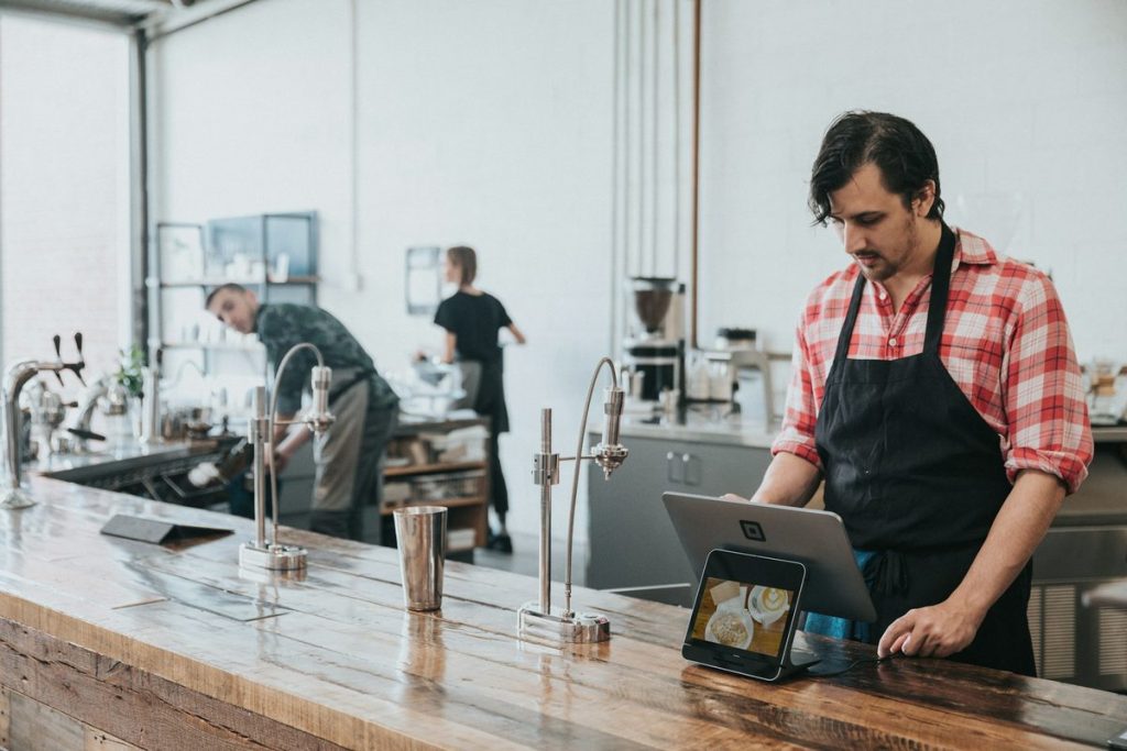 AI for restaurant marketing: a cafe owner checks a tablet at the counter during service