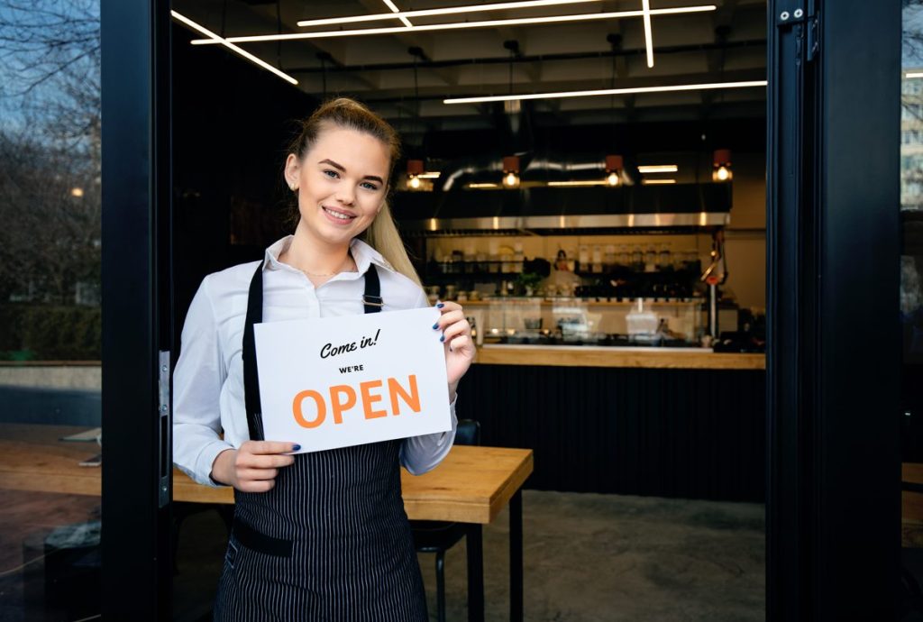 How to attract more customers in my restaurant: owner holding an open sign at the door
